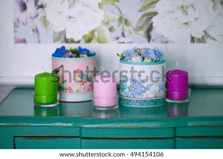 Candles and flower decorative boxes on a green chest of drawers
