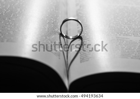 ring casting a heart-shaped shadow on the book page