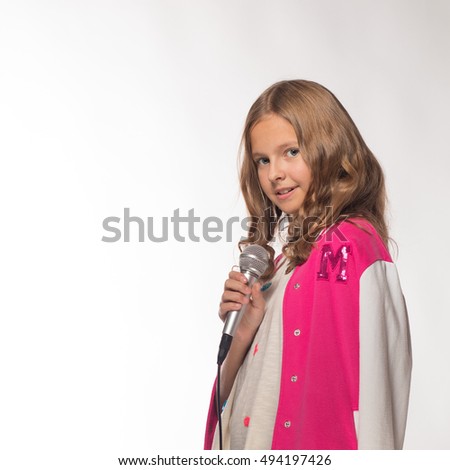 Emotional blonde girl in a pink jacket with a microphone