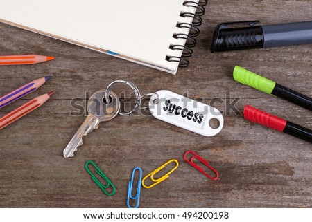 Old key With Success Text. Wooden texture background with pencils, pens and notepad 