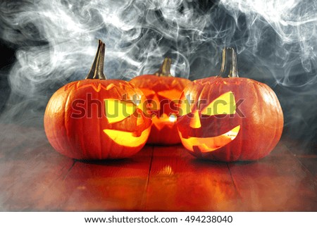 orange pumpkin on wooden desk and halloween time with black background of smoke 