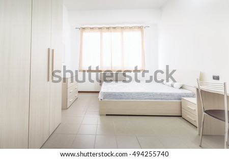 Simple student-style dorm bedroom with lots of light Royalty-Free Stock Photo #494255740