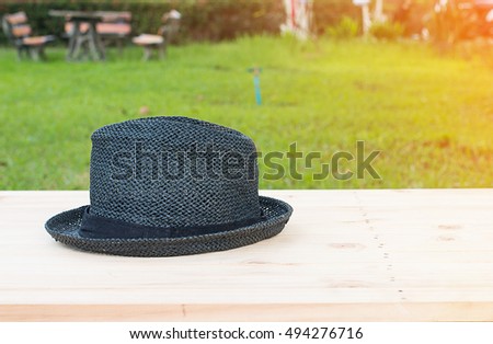 hat on on wood terrace over green nature background.