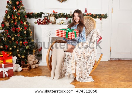 Beautiful girl in a Christmas room with the gift of hands in a rocking chair