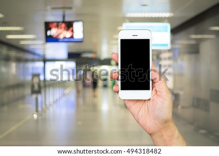 Woman hand holding and using mobile,cell phone,smart phone with isolated screen with blurred of corridor inside the metro station.