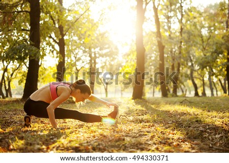 Young woman is stretching outdoors in park 