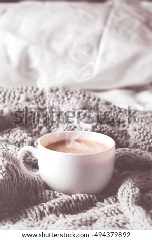 Having a cup of coffee on gray blanket in bed. Instagram toned photo