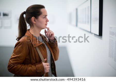 Portrait of longhaired brunette girl in leather jacket at gallery exhibition
