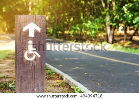 Symbol of the disabled in park with road and sunshine background.