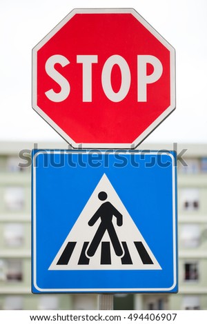 Pedestrian and Stop traffic sign. The background blurry buildings and sky.