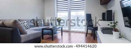 Panorama of new house interior with window, large sofa, floor panels and white furniture set