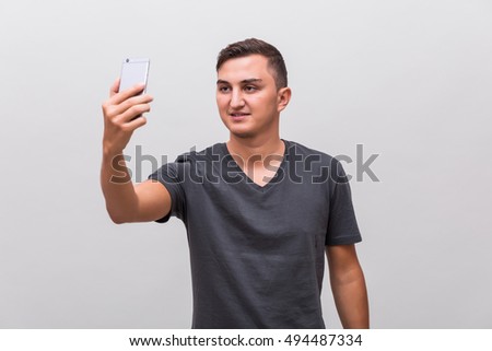 Portrait of a smiling man making selfie photo over gray background