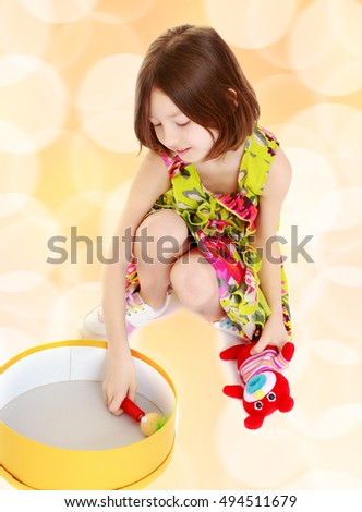 Cute little skinny girl plays with a round box.Brown festive, Christmas background with white snowflakes, circles.