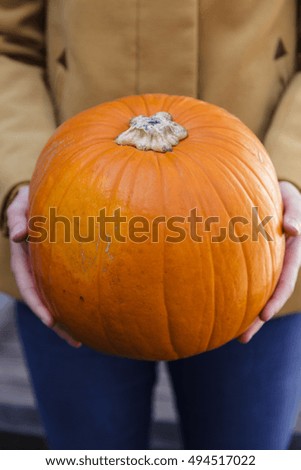 Young woman holding orange pumpkin