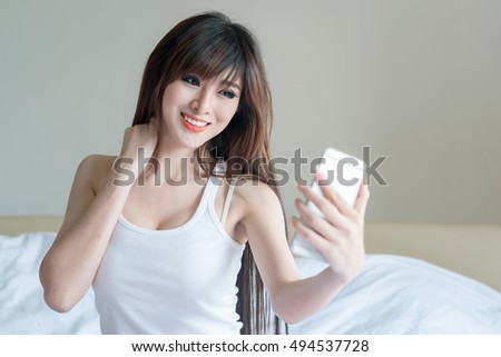 Smiling young girl making selfie photo on smartphone in the bedroom