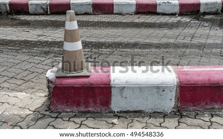 Old Plastic cone on the red and white curb
