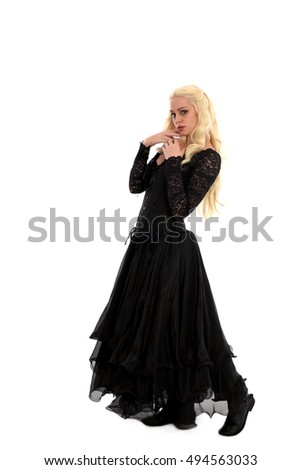 beautiful blonde woman wearing a long black gothic gown, with raven feathers standing pose isolated on white background.