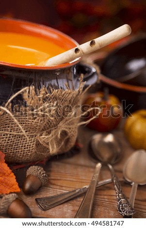 A pot of homemade creamy pumpkin soup on a rustic table with autumn decorations.