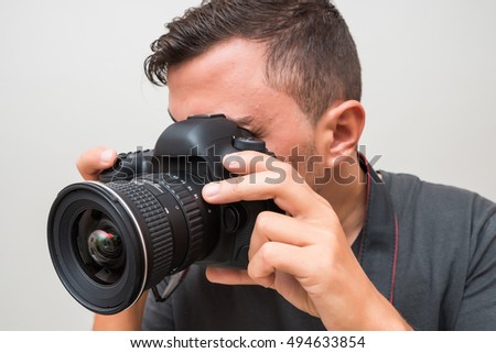 Portrait of a male photographer with camera taking photo isolated on a gray background