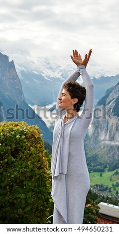 Beautiful young, slim, short-haired caucasian woman standing in a long dress on the mountain background. Travel concept. Freedom concept. Swiss Alps