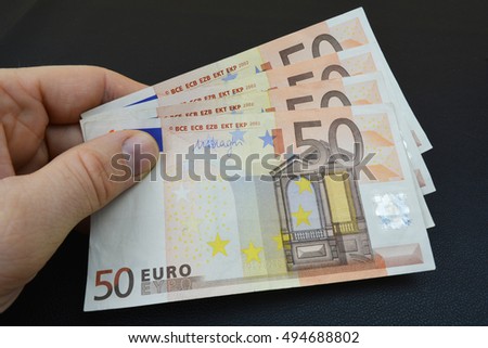 Several fifty euros in hand. Bundle of euros. European banknotes, money in hand. Black background