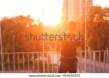 nostalgic young man testing a pair of VR glasses with hands touching virtual reality in a cool sweater and trendy outfit curious by augmented reality sunlit by an amazing LOW LIGHT sunset soft focus