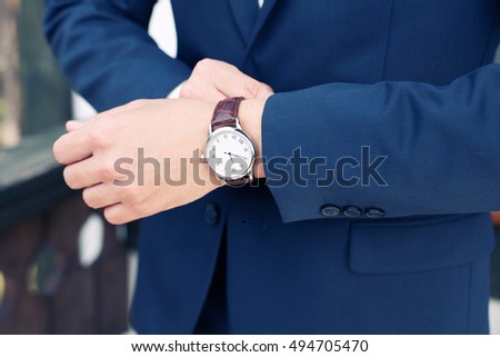 closeup designer watch on businessman hand, he looks on the time and hurrying Royalty-Free Stock Photo #494705470