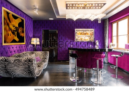 Bold violet and pink colours in the room with striped couch