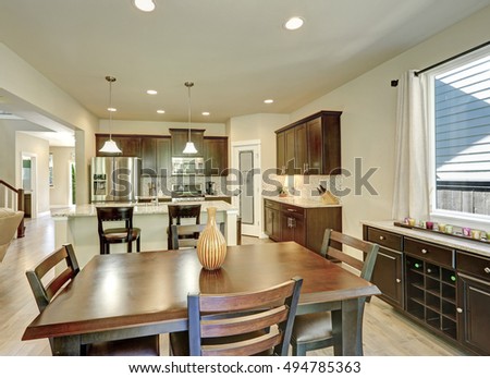 Dining and kitchen room interior in brand-new house. Dark brown furniture and hardwood floor. Northwest, USA