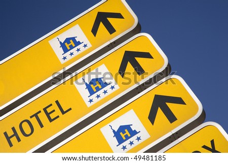 Cropped close-up of a group of yellow signs with arrows showing the way to hotels. Horizontal shot.