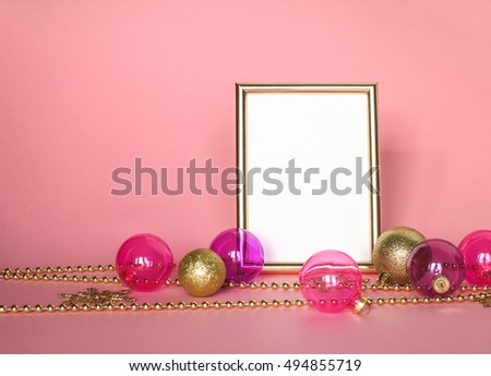 Gold picture frame with christmas ornaments. Mockup on pink background. Fashion decoration