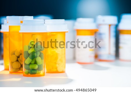 Numerous pill bottles of different prescription capsule tablet pill medicine medications in dramatic blue atmosphere Royalty-Free Stock Photo #494865049