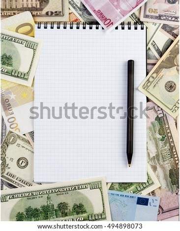 Opened spiral notepad (notebook) sheet in a cage on money background ( euro and dollars cash). with black pen