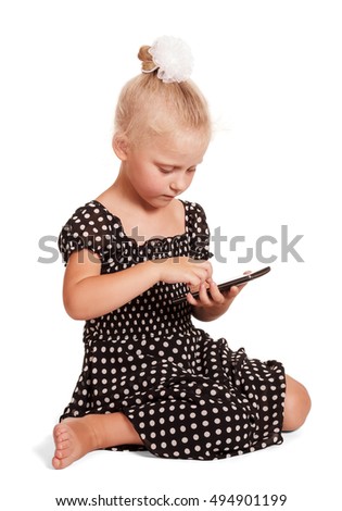 Little girl in a dark dress polka dots while sitting calls mobile isolated on white background.