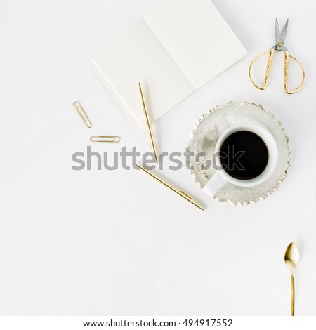 coffee cup, empty diary and golden accessories: tea spoon, pen, clips and scissors on white background. flat lay, top view