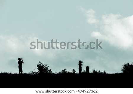 Silhouette of a standing photographer  over blue sky in a landscape