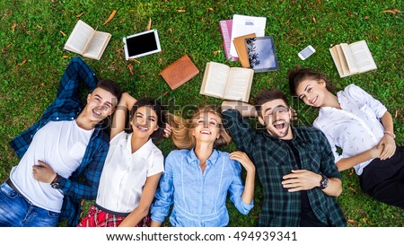 Having the best time with friends. Top view of a group of students lying on the grass enjoying their break. Royalty-Free Stock Photo #494939341