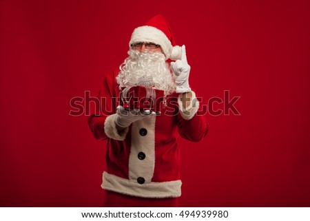 Photo of kind Santa Claus giving xmas present and looking at cam