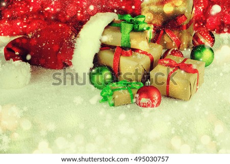 Santa Claus red bag with Christmas balls and gift box on snow.
