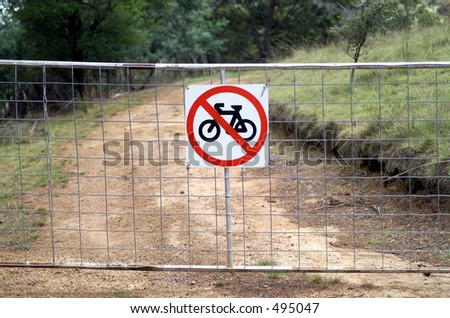 No Bicycle sign attached to a gate across a dirt road