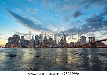 The Manhattan skyline and Brooklyn Bridge as seen from across the East River at dusk. New York City at night.