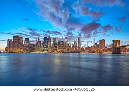The Manhattan skyline and Brooklyn Bridge as seen from across the East River at dusk. New York City at night.