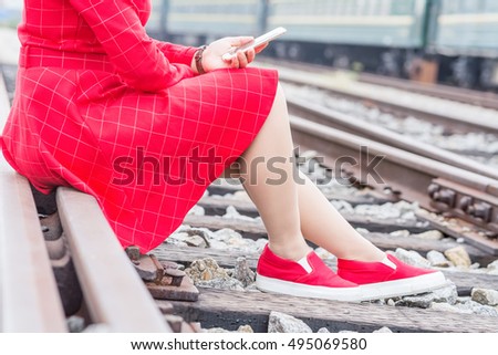young woman using smart phone at Railroad tracks 