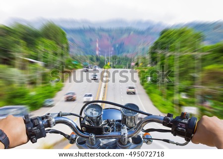 Man riding motorcycle, blur image of motion on the road as background.