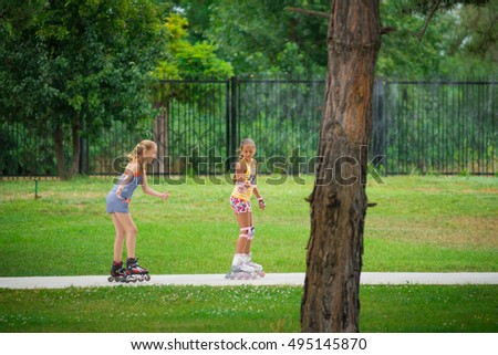 Active young people - rollerblading. Two girls rollerblading. Two attractive teen female friends roller skating in park. two girls spend a fun free time in sports. motion blur
