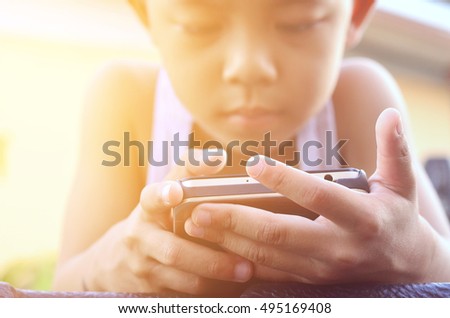 Cute boy using a mobile phone outdoors on sunset . Technology generation.