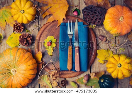 Thanksgiving dinner background with round board. Autumn pumpkin and fall leaves on wooden table. View from above