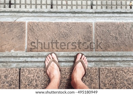 young man standing with top view of Pair of sandal on brick concrete floor.