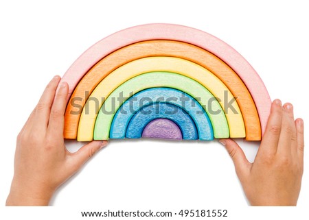 Hands with wooden puzzle in the form of a rainbow isolated on white. Multicolored toy. 