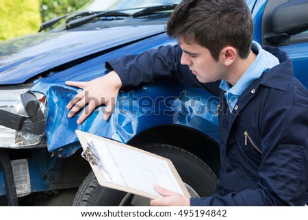Auto Workshop Mechanic Inspecting Damage To Car And Filling In Repair Estimate Royalty-Free Stock Photo #495194842